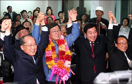 25일 밤 당선이 유력한 김홍업 후보가 지지자들로부터 받은 축하 꽃다발을 목에 걸고 이낙연 의원, 열린우리당을 탈당한 전병헌 의원 등과 함께 손을 들어 답례하고 있다. 